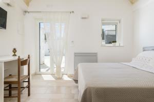 a white bedroom with a bed and a desk at Masseria Abadia Uno in Ostuni