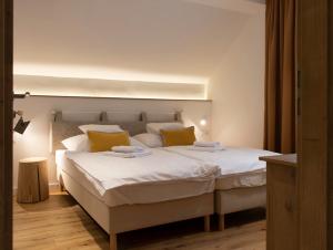 1 dormitorio con 1 cama blanca grande con almohadas amarillas en Hegyalja Étterem és Panzió en Zsámbék