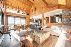 un soggiorno con un divano e un tavolo di Chalet Lumière - LaGodille Prestige - 16 personnes - Pra Loup a Uvernet