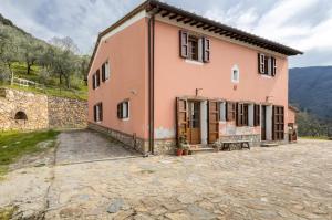 ein großes rosafarbenes Haus mit einem steinernen Innenhof in der Unterkunft Olive House Tuscany in Calci