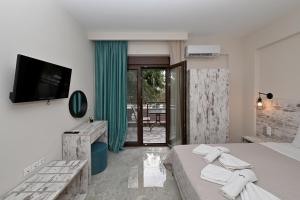 a bedroom with a bed and a television and a balcony at Sinodinos Deluxe Apartments in Afitos