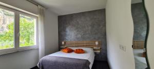 - une chambre dotée d'un lit avec deux oreillers orange dans l'établissement La Casa Verde Torbole, à Nago-Torbole