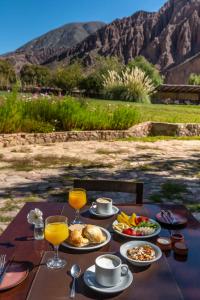 einen Tisch mit Teller mit Lebensmitteln und Gläsern Orangensaft in der Unterkunft Hotel El Manantial del Silencio in Purmamarca