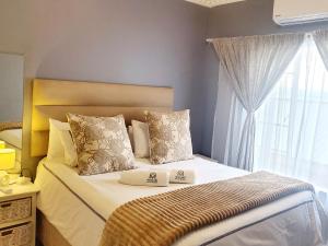 a bedroom with a large bed with a window at Mnqobi Lifestyle Apartments in Nelspruit