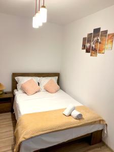 una camera da letto con un letto con lenzuola bianche e cuscini rosa di CRISTAL Home Boutique Apartment 1 - Confort, Spatios, Linistit, Zona de interes a Craiova