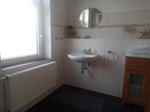 ein weißes Badezimmer mit einem Waschbecken und einem Spiegel in der Unterkunft Ferienwohnung am Kurpark Ostrau in Bad Schandau