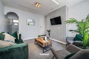 uma sala de estar com mobiliário verde e uma televisão em NEW Lime House by Truestays - 3 Bedroom House in Stoke-on-Trent em Stoke-on-Trent