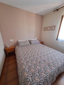 een slaapkamer met een bed met een dekbed en een raam bij Casa apareada cerca de la playa in Torredembarra