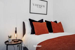 um quarto com uma cama com almofadas laranja e branca em NEW Lime House by Truestays - 3 Bedroom House in Stoke-on-Trent em Stoke-on-Trent