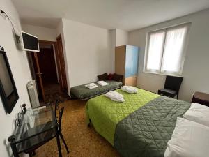 ein Hotelzimmer mit 2 Betten und einem TV in der Unterkunft YOLO Rooms in Bonassola