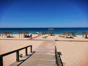 una passerella sulla spiaggia con persone sulla spiaggia di Casa da Avó ad Alcácer do Sal