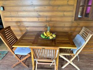 una mesa de madera y sillas con un bol de fruta. en Gîtes Hotel Couleur Caraibes, en Bouillante