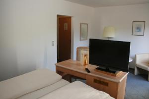 a bedroom with a bed and a television on a desk at Landhotel Burkartsmühle in Hofheim am Taunus
