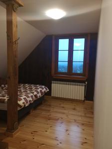 1 dormitorio con cama y ventana grande en Osada na Granicy - Domki w Bieszczadach, en Ustrzyki Dolne