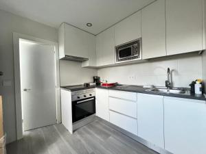 eine Küche mit weißen Schränken, einer Spüle und einer Mikrowelle in der Unterkunft Gran Piso Retiro Corregidor in Madrid
