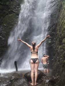 een man en een vrouw die voor een waterval staan bij Hostal Casa del Viento Kitesurf & Adventure in Calima