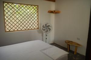 1 dormitorio con 1 cama, ventilador y ventana en Ipqua Hostel, en Palomino