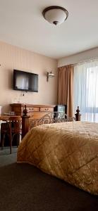 a bedroom with a bed and a table and a television at Jaukūs Friedricho pasažo apartamentai in Klaipėda