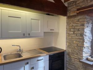 a kitchen with white cabinets and a sink and a stone wall at Harvest End in York