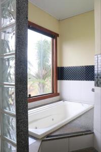 a bath tub in a bathroom with a window at Hotel Fazenda da Lagoa in Queluzita