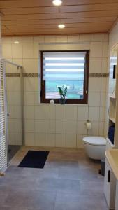 a bathroom with a toilet and a window with a flower in it at Ferienwohnung Schmidt in Airlenbach