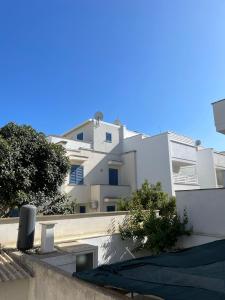 un edificio de apartamentos blanco con árboles delante de él en villa TiCia a 100 metri dalla spiaggia con parcheggio privato, en Lido Marini