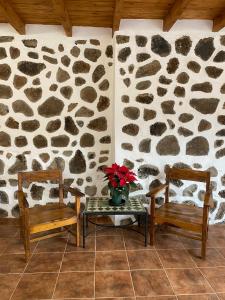 una habitación con dos bancos y una mesa con flores. en Vallechico, en Vallebrón