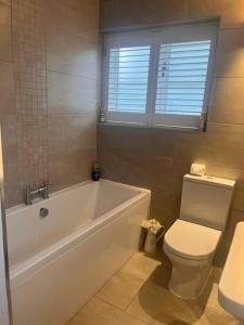 a bathroom with a white tub and a toilet at 2 Bedroom Barn Conversion in Leicester