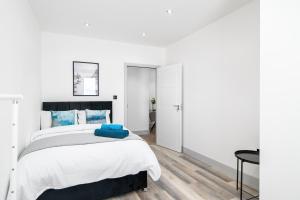 ein weißes Schlafzimmer mit einem Bett und einem Tisch in der Unterkunft Livestay-Modern Apartments in Romford near Elizabeth Line in Romford