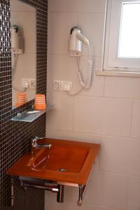 La salle de bains est pourvue d'un lavabo brun et d'un miroir. dans l'établissement Alojamentos Vitinho - Vila Nova Milfontes, à Vila Nova de Milfontes