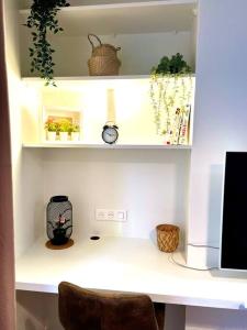 a white desk with shelves with plants and a clock at Deux pièces familial chic et confortable - Square Courteline - Nation - Paris centre in Paris