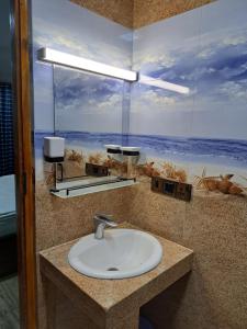 een badkamer met een wastafel en een foto van de oceaan bij The Surf Access Guest House in Arugam Bay