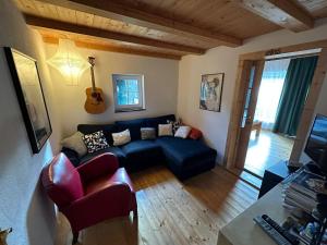 a living room with a blue couch and a guitar at VillaVoigt, een Gezellig Familiehuis in Äussere Kainisch