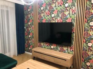 einen TV an der Wand mit Blumentapete in der Unterkunft Solankowa Aleja Apartament Egzotyczny in Inowrocław