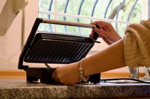 a woman is using a toaster on a counter at Vasiliki's Apartment in Psakoudia