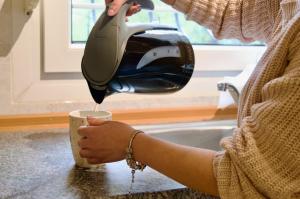 a woman pouring coffee into a coffee cup at Vasiliki's Apartment in Psakoudia