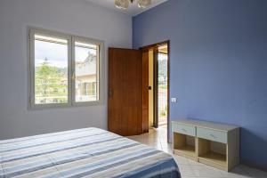 a blue bedroom with a bed and a window at Corbezzolo in Bari Sardo