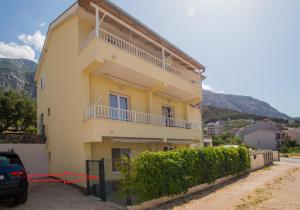 a yellow house with a car parked in front of it at Apartman Domenika in Makarska