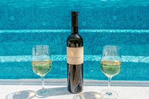 una bottiglia di vino e due bicchieri di vino accanto alla piscina di Apartment Anitea a Pola (Pula)