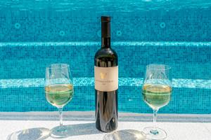 a bottle of wine and two wine glasses next to a swimming pool at Apartment Anitea in Pula