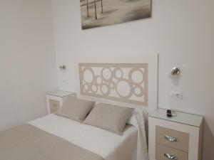 ein weißes Schlafzimmer mit einem Bett mit zwei Nachttischen in der Unterkunft Hostal Los Arcos in Chipiona