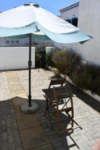 a chair and an umbrella next to a bench at Alojamentos Vitinho - Vila Nova Milfontes in Vila Nova de Milfontes