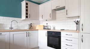 a kitchen with white cabinets and a black dishwasher at Bassicks at the Graythwaite Estate in Ulverston