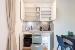 a small kitchen with white cabinets and a blue chair at HITrental Riesbach Apartments in Zürich