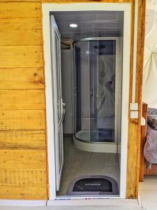 una puerta de cristal que conduce a una ducha en una habitación en 4 seasons. 4 სეზონი Glamping Georgia Racha en Ambrolauri