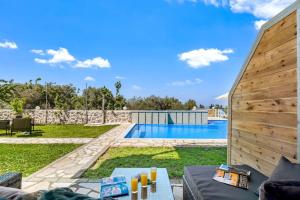 a backyard with a swimming pool and a wooden wall at Sea view apartments in Tsoukalades