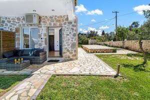 uma casa de pedra com um jardim e um pátio em Sea view apartments em Tsoukaladhes