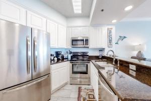 a kitchen with white cabinets and a stainless steel refrigerator at Palm Beach C52 in Orange Beach