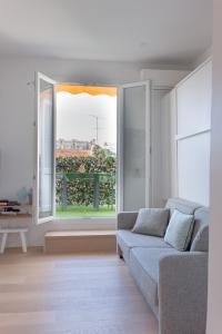 uma sala de estar com um sofá e uma grande janela em Un Écrin au Suquet - Studio, clim, balcon, plage, Palais des Festivals em Cannes