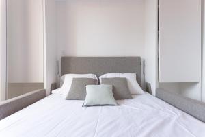 a bed with white sheets and pillows on it at Un Écrin au Suquet - Studio, clim, balcon, plage, Palais des Festivals in Cannes